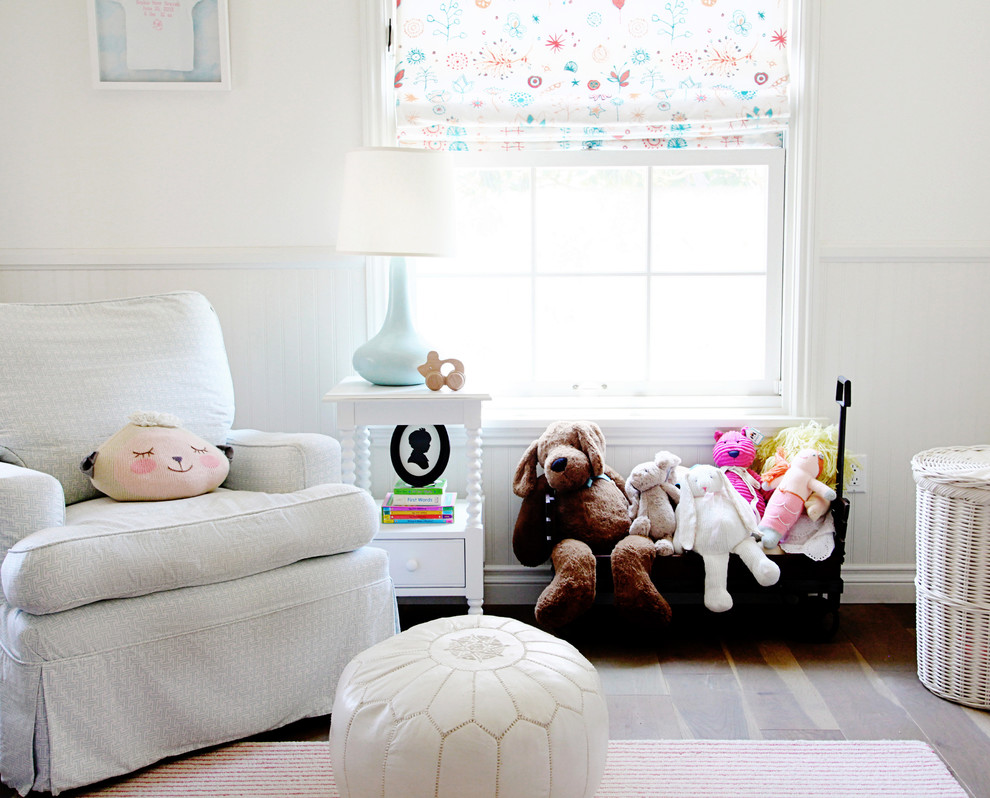 Esempio di una cameretta per neonata tradizionale di medie dimensioni con pareti bianche e parquet chiaro