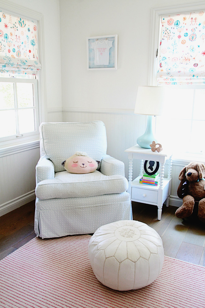 Idée de décoration pour une chambre de bébé fille tradition de taille moyenne avec un mur blanc et parquet clair.