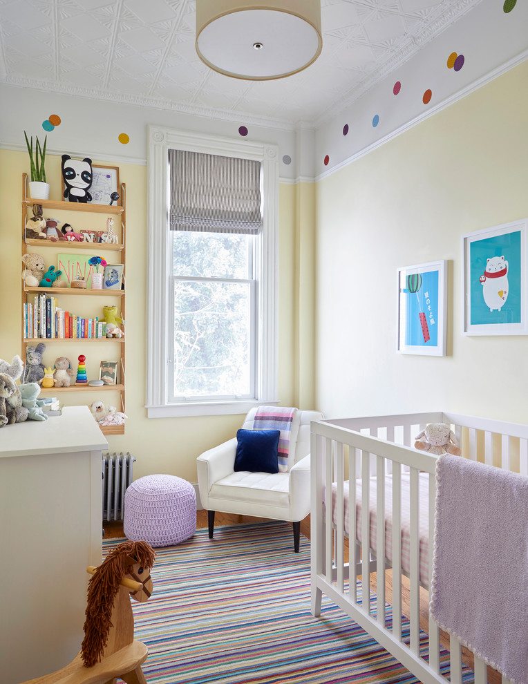Photo of a scandinavian gender neutral nursery in New York with yellow walls, medium hardwood flooring and beige floors.