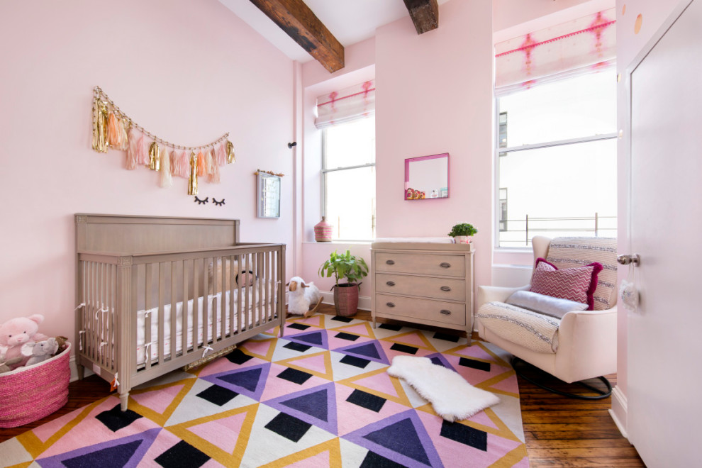 Esempio di una cameretta per neonata chic con pareti rosa e pavimento in legno massello medio