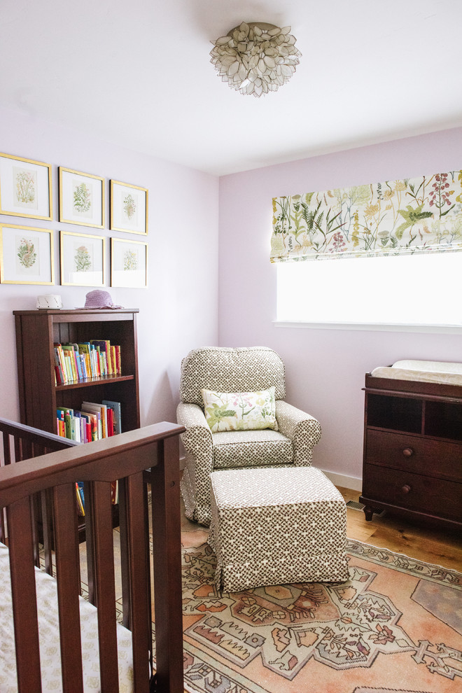 Immagine di una piccola cameretta per neonata boho chic con pareti viola e pavimento in legno massello medio