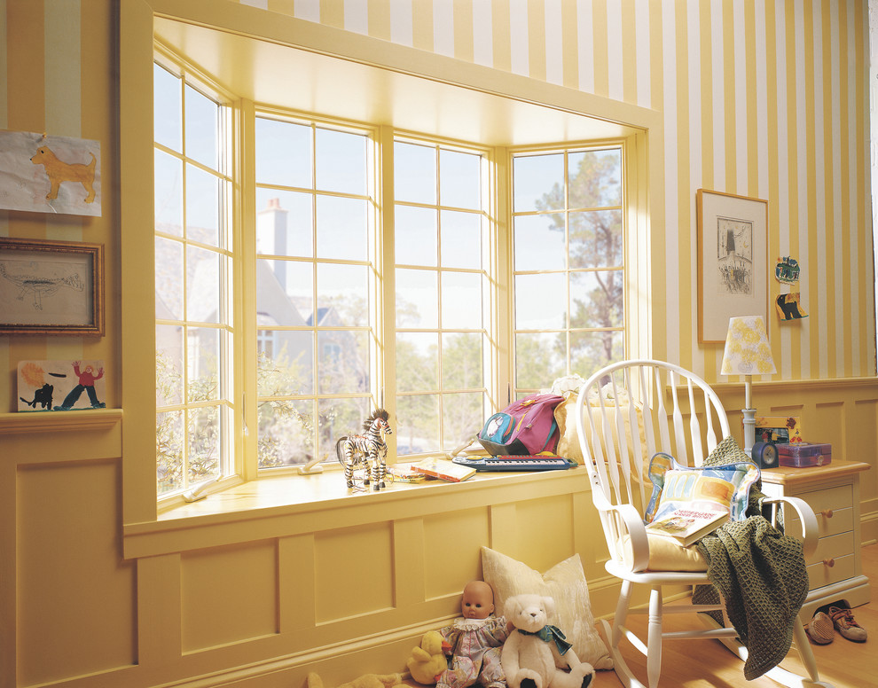 Foto de habitación de bebé neutra clásica de tamaño medio con paredes amarillas y suelo de madera clara