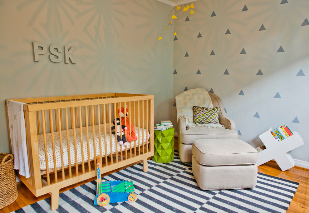 Foto de habitación de bebé moderna pequeña con paredes blancas y suelo de madera en tonos medios