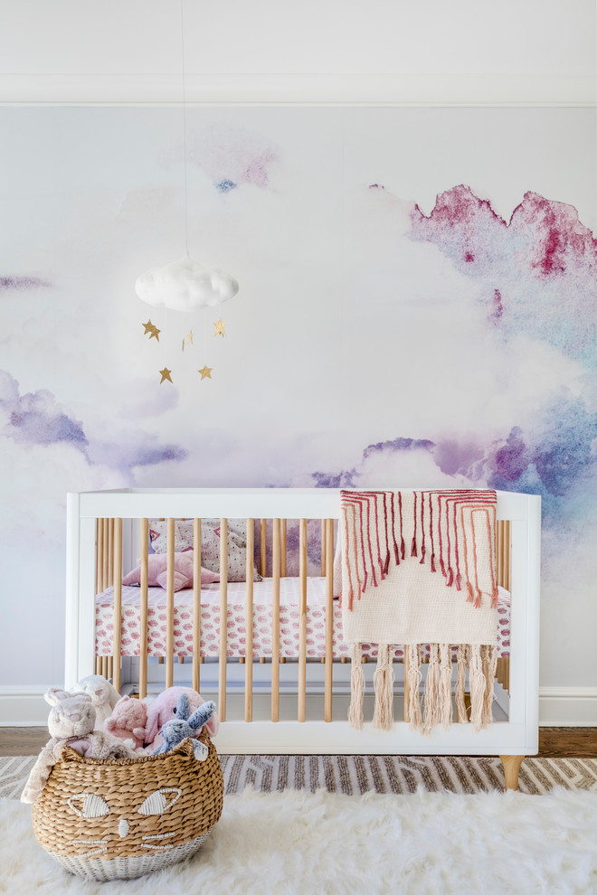 Immagine di una cameretta per neonata classica di medie dimensioni con pareti multicolore e pavimento in legno massello medio