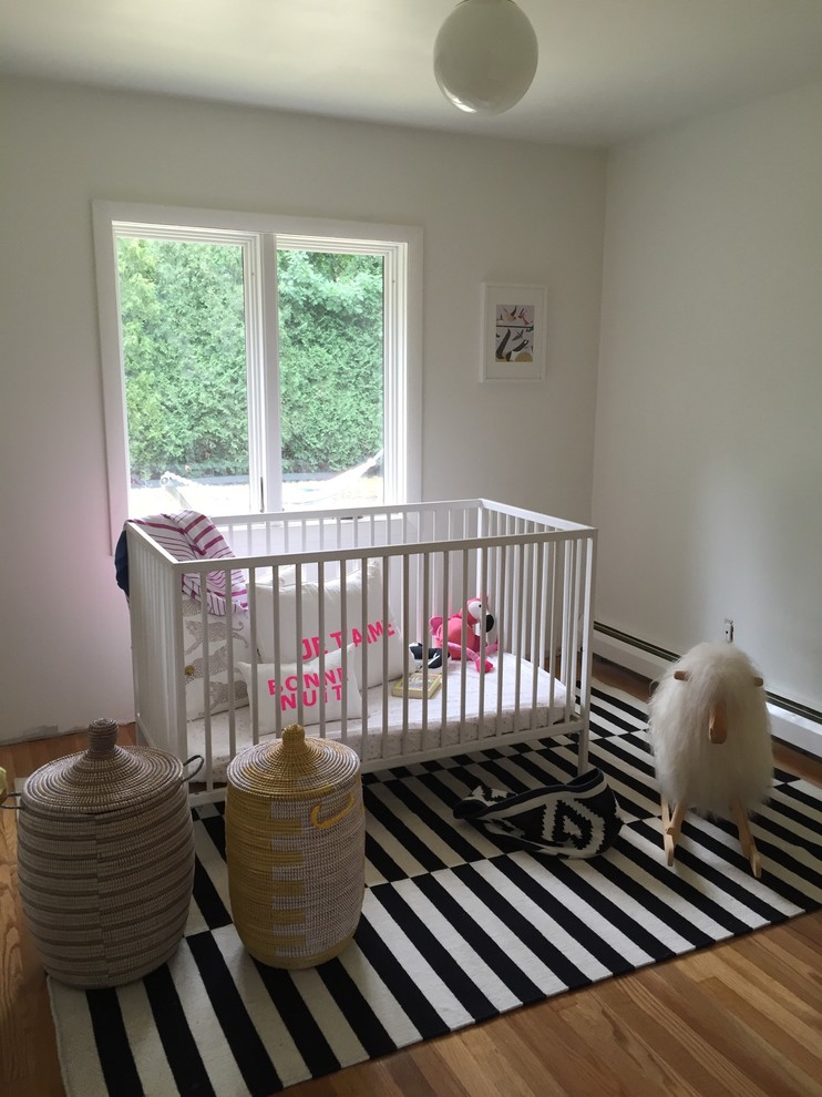 Imagen de habitación de bebé neutra vintage pequeña con paredes blancas y suelo de madera clara