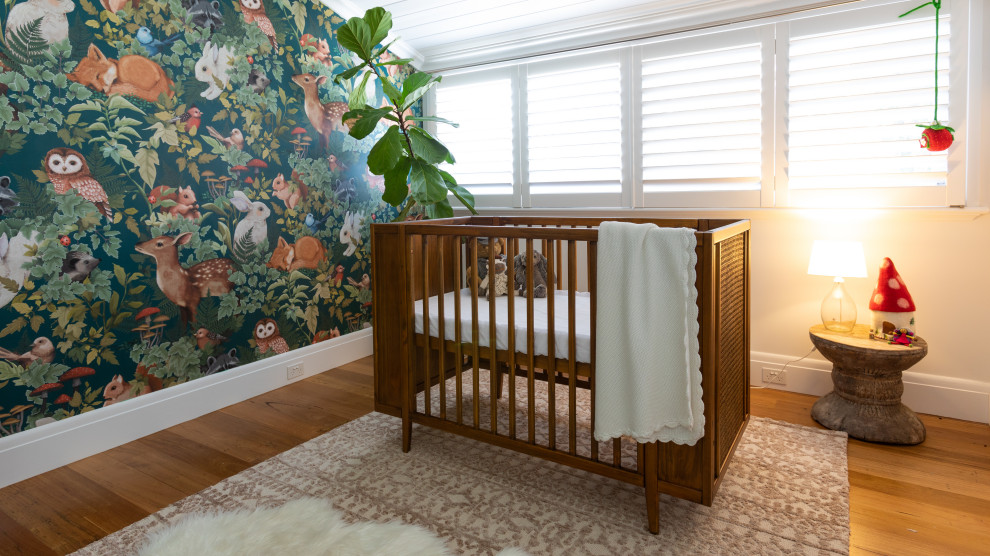 Cette image montre une chambre de bébé neutre rustique de taille moyenne avec un mur multicolore, un sol en bois brun et du papier peint.