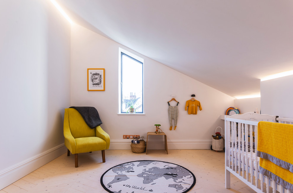 Modelo de habitación de bebé neutra contemporánea grande con paredes blancas y suelo de madera clara