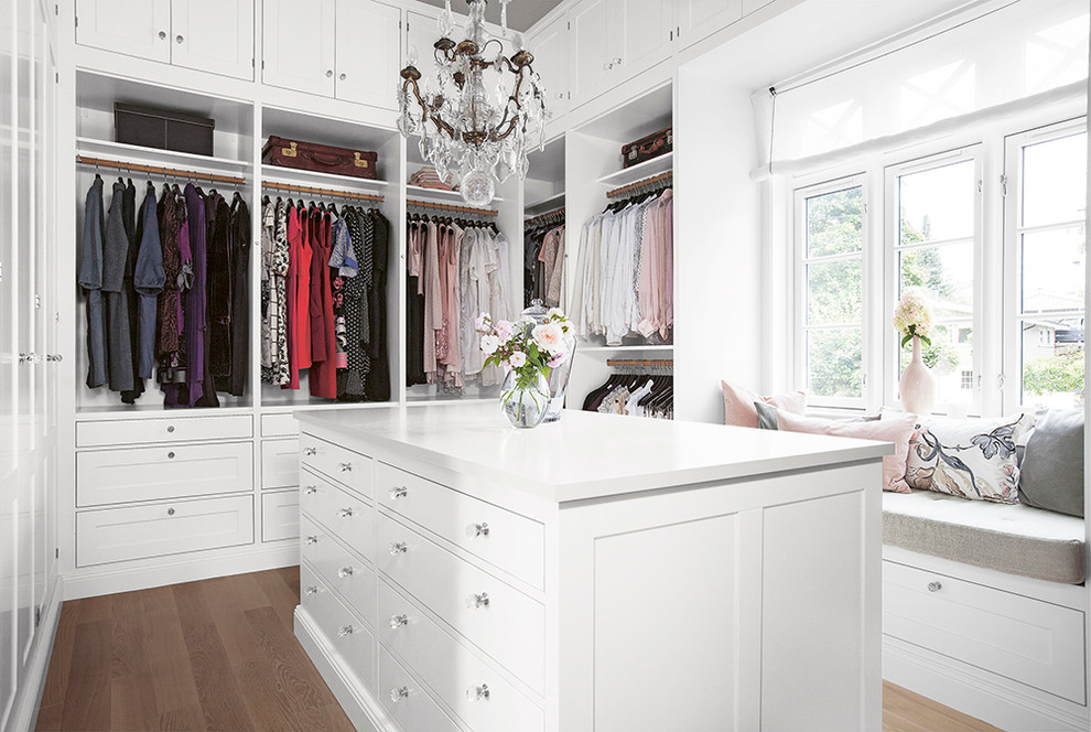 Modelo de vestidor de mujer clásico renovado grande con armarios con paneles empotrados, puertas de armario blancas y suelo de madera oscura