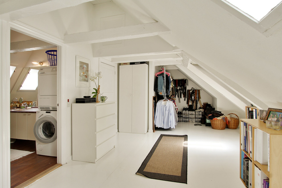 Immagine di uno spazio per vestirsi unisex nordico di medie dimensioni con ante bianche e pavimento in legno verniciato