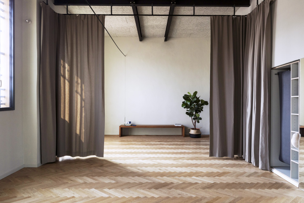 Photo of a large scandinavian home yoga studio in Milan with white walls, light hardwood flooring and beige floors.