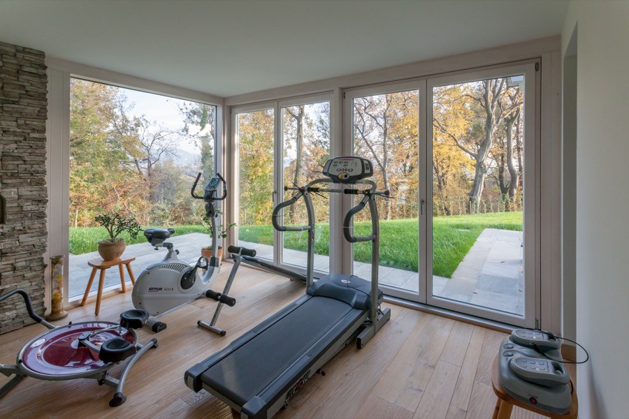 Multifunktionaler, Mittelgroßer Country Fitnessraum mit weißer Wandfarbe und braunem Holzboden in Sonstige