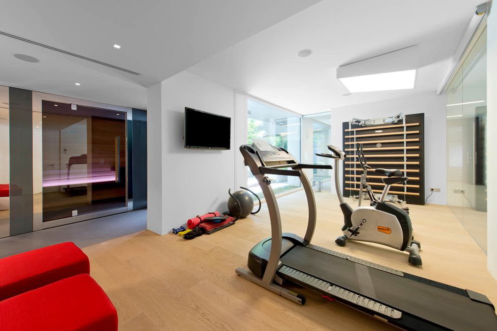 Multifunktionaler Moderner Fitnessraum mit weißer Wandfarbe und hellem Holzboden in Sonstige