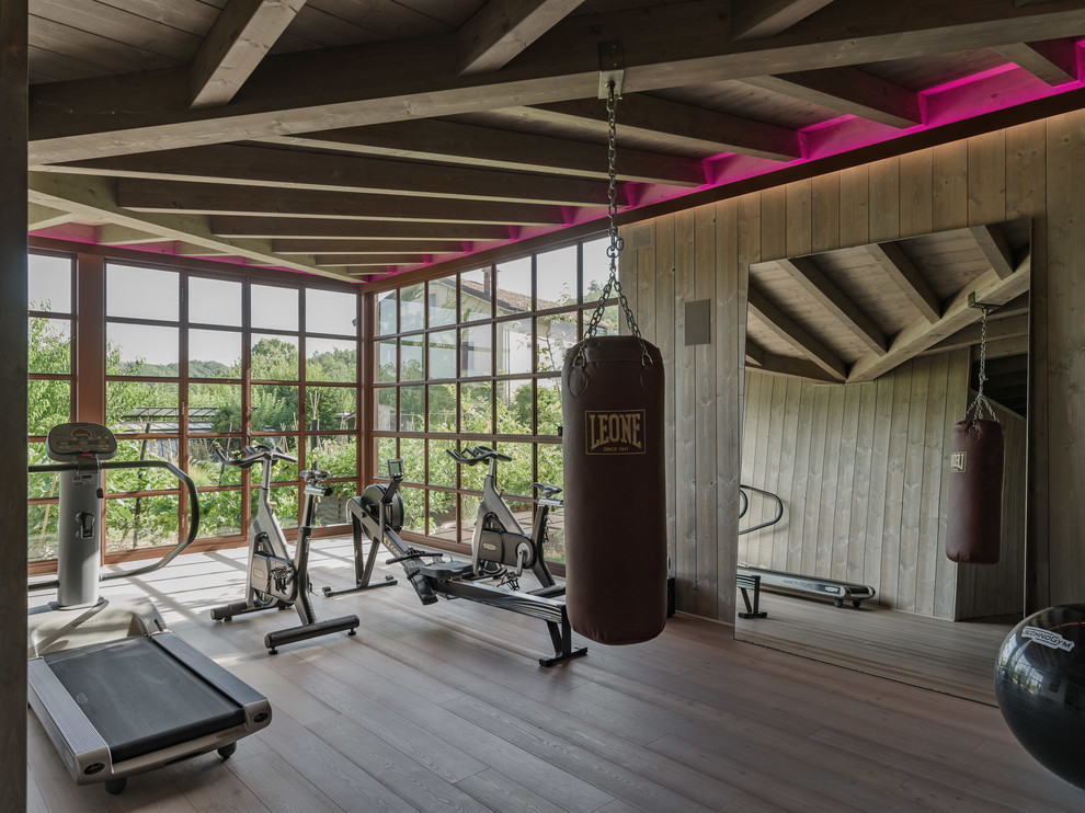 Multifunktionaler, Großer Moderner Fitnessraum mit grauer Wandfarbe, braunem Holzboden und grauem Boden in Sonstige