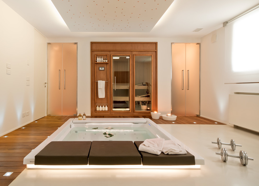 Foto di una palestra multiuso contemporanea con pareti bianche e pavimento in legno massello medio