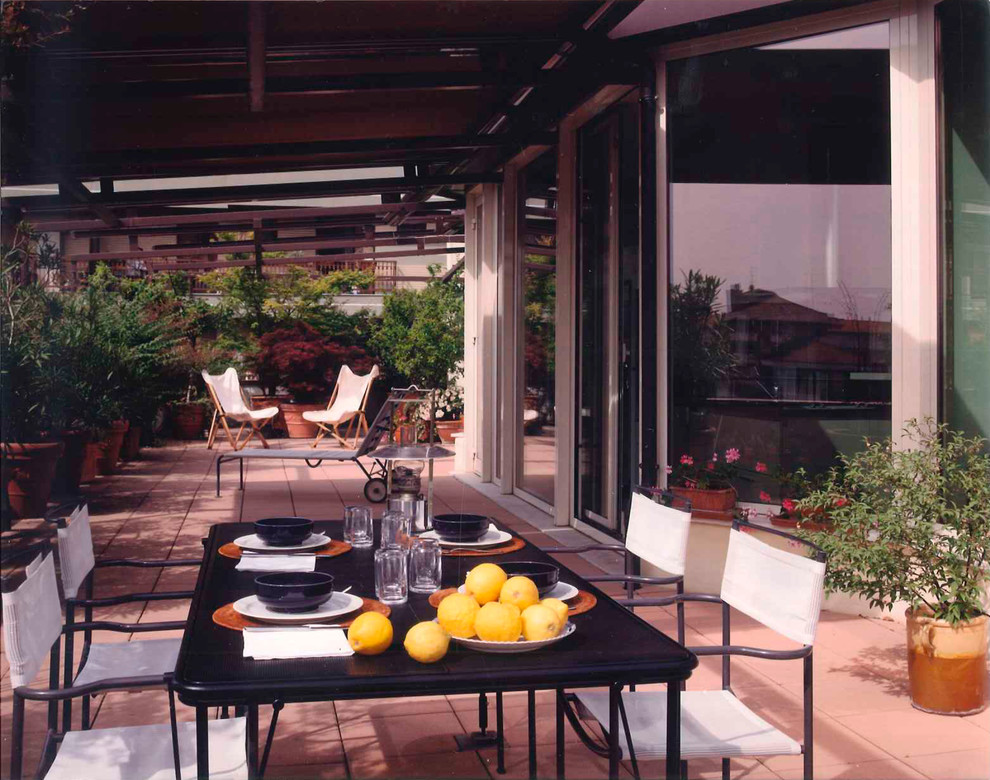 Foto di un grande patio o portico mediterraneo con un giardino in vaso e un parasole