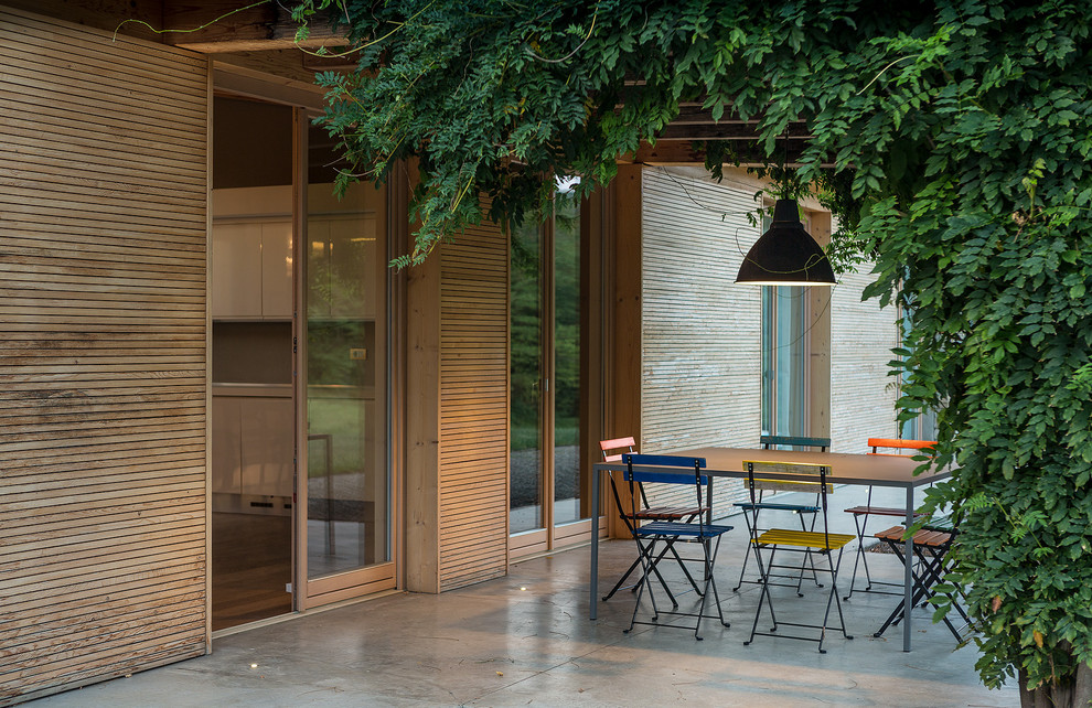 Esempio di un patio o portico minimal di medie dimensioni con lastre di cemento e una pergola