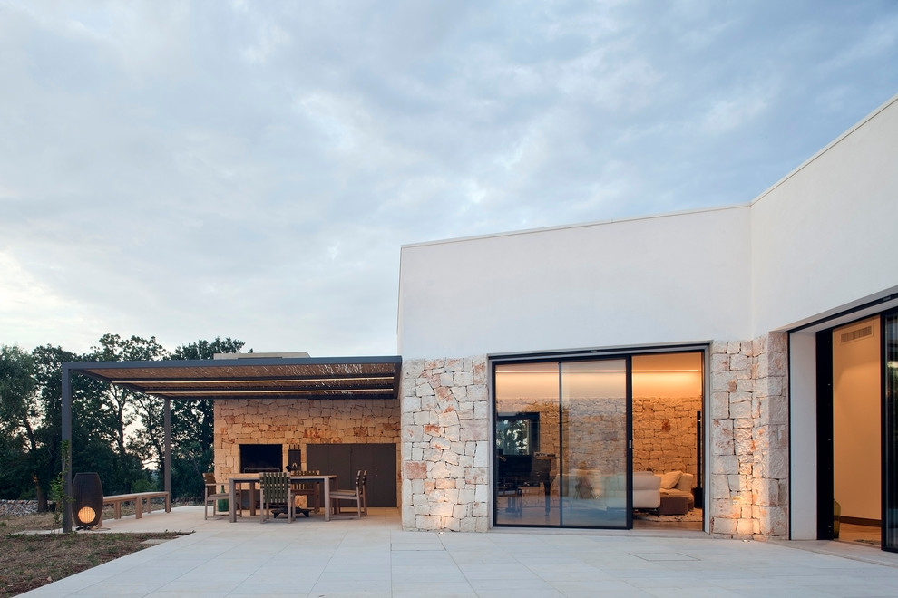 Mittelgroße Mediterrane Pergola hinter dem Haus mit Kamin und Natursteinplatten in Sonstige