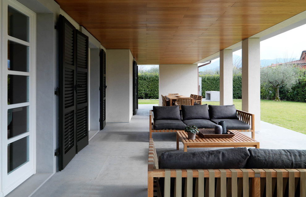 Ispirazione per un patio o portico minimalista di medie dimensioni con pavimentazioni in cemento e un tetto a sbalzo