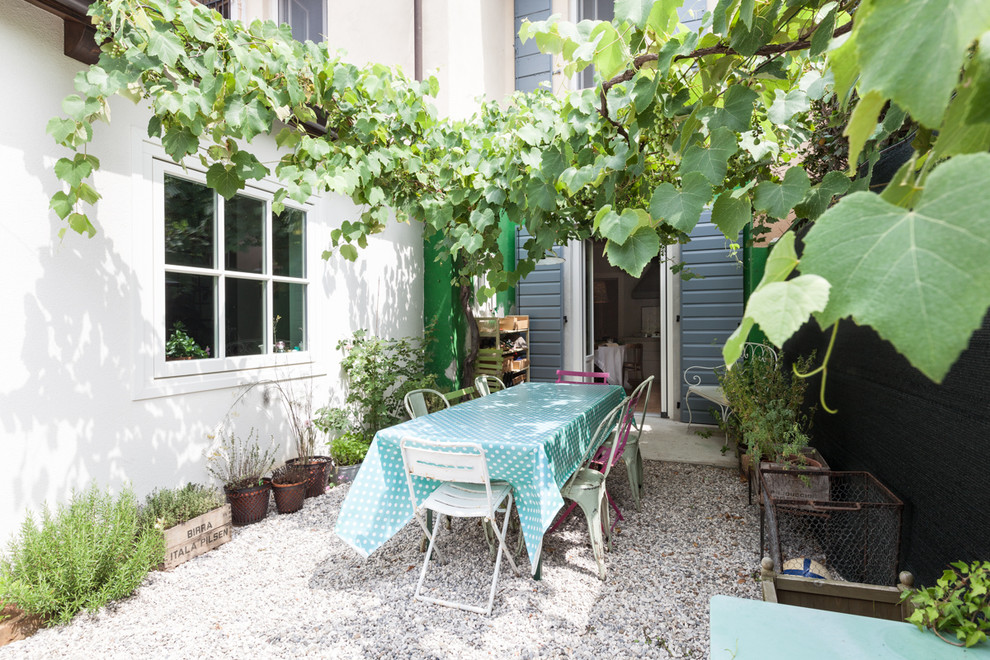 Imagen de patio de estilo de casa de campo pequeño en patio con jardín de macetas y gravilla