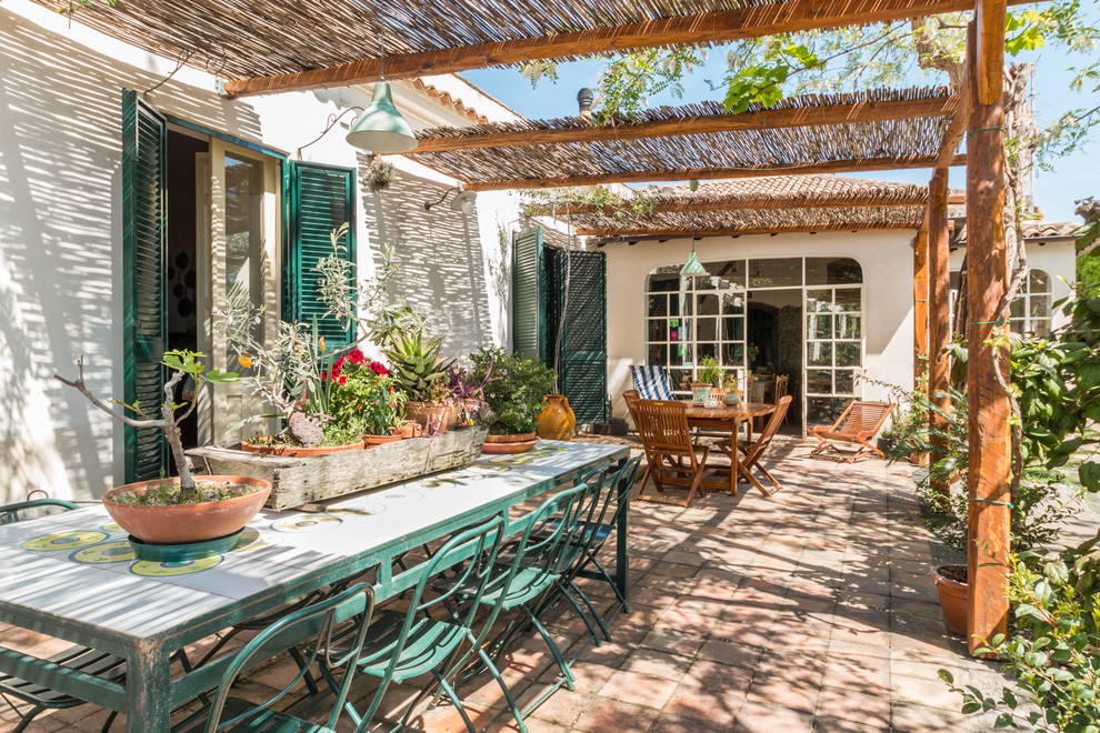 Foto de patio mediterráneo con jardín de macetas, adoquines de ladrillo y pérgola