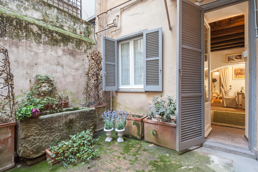 Farmhouse patio in Rome with a potted garden, brick paving and no cover.