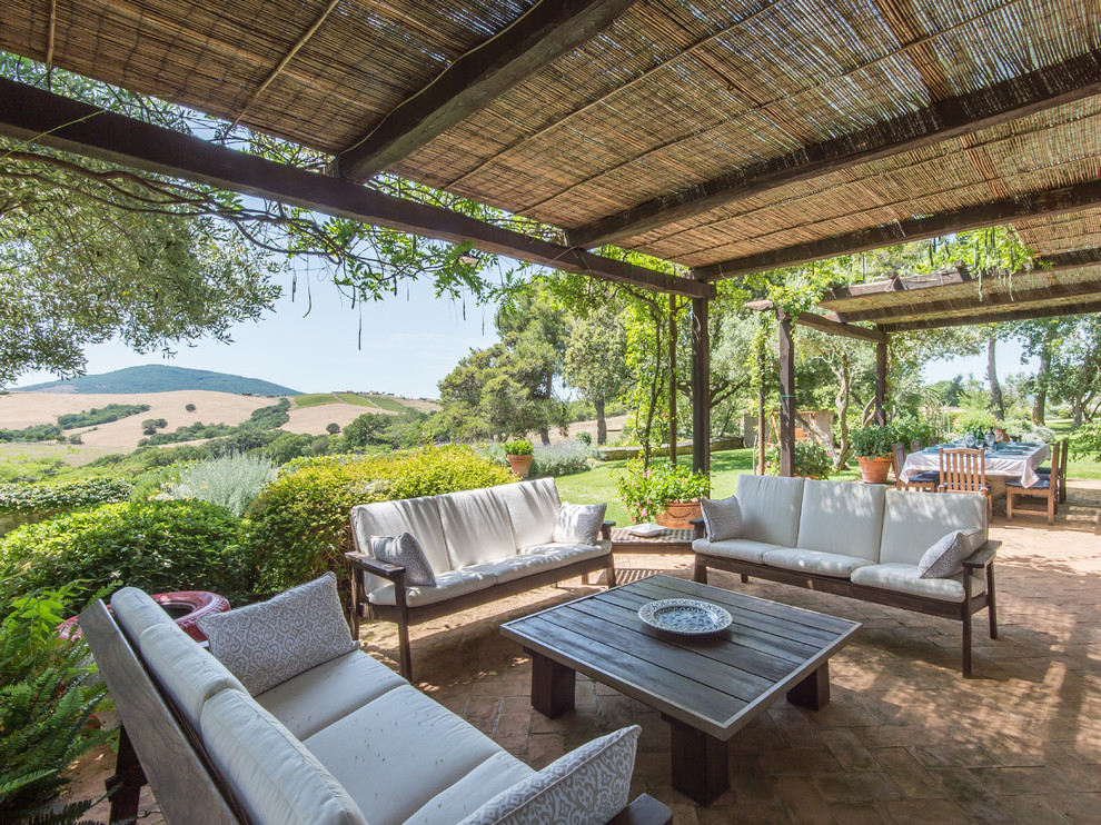 Foto de patio de estilo de casa de campo grande en patio lateral con adoquines de ladrillo y pérgola