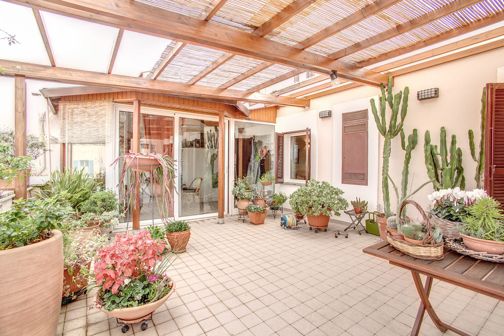 Immagine di un patio o portico boho chic nel cortile laterale con un giardino in vaso, piastrelle e una pergola