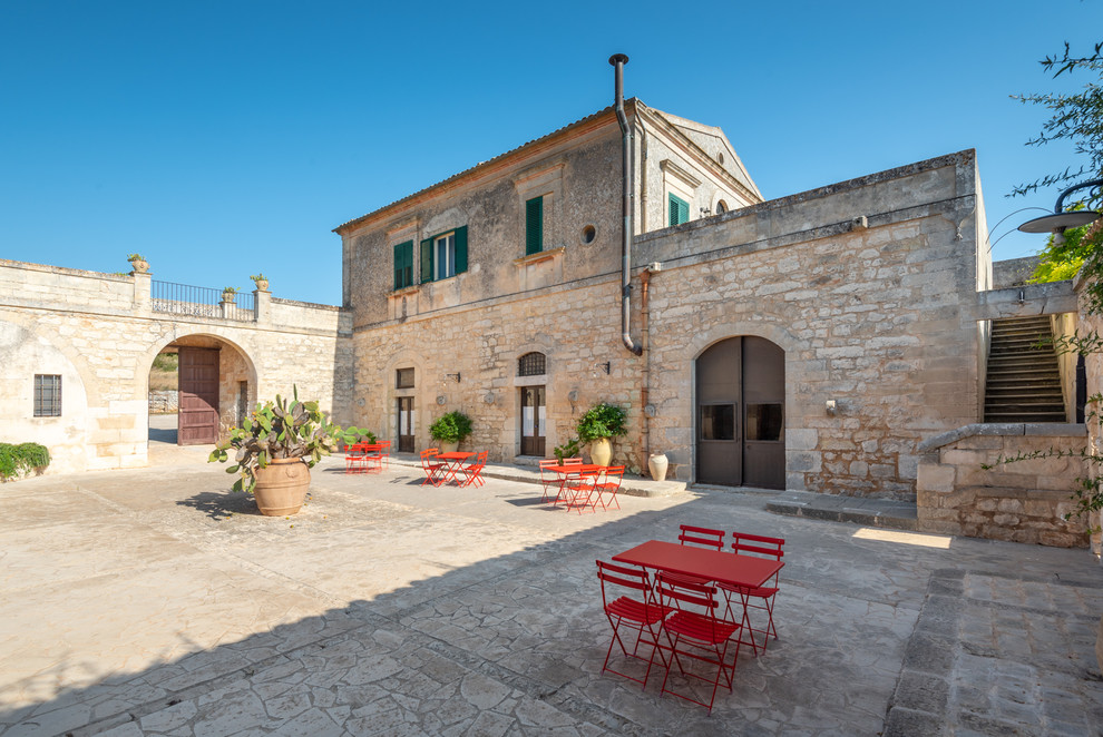 Foto di un grande patio o portico mediterraneo in cortile con un giardino in vaso, pavimentazioni in pietra naturale e nessuna copertura