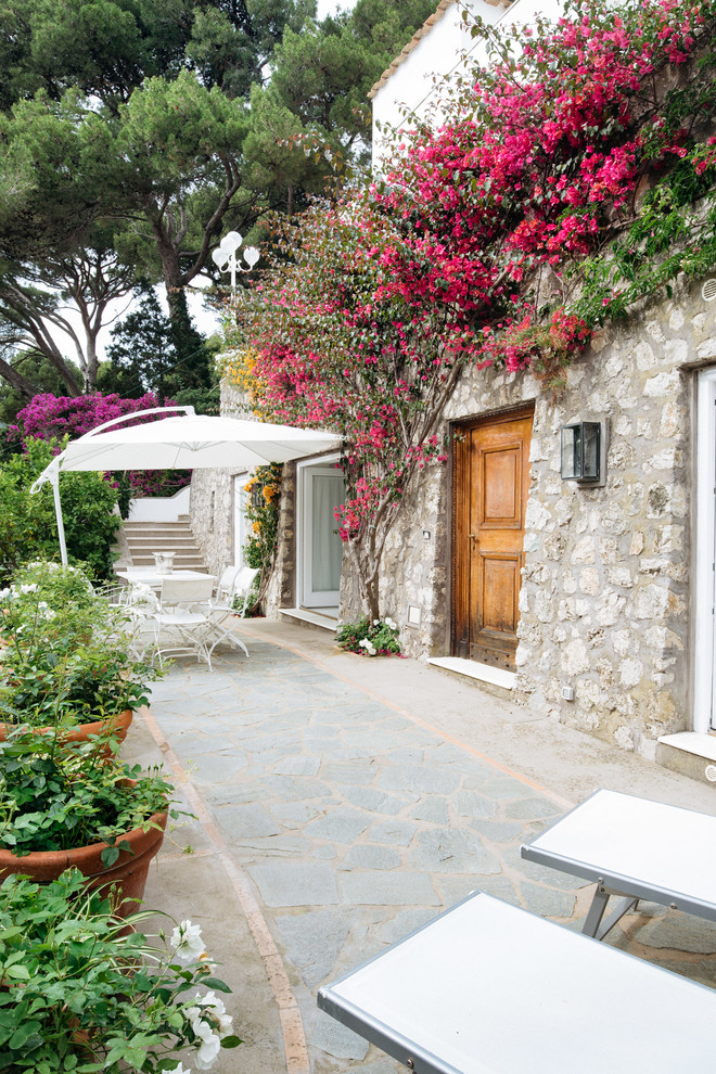 На фото: двор на боковом дворе в средиземноморском стиле с растениями в контейнерах и покрытием из каменной брусчатки с