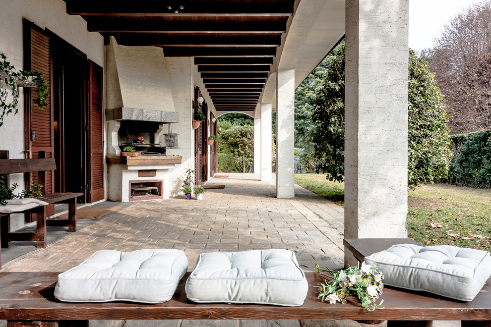 На фото: большой двор на заднем дворе в стиле кантри с покрытием из каменной брусчатки, летней кухней и навесом с