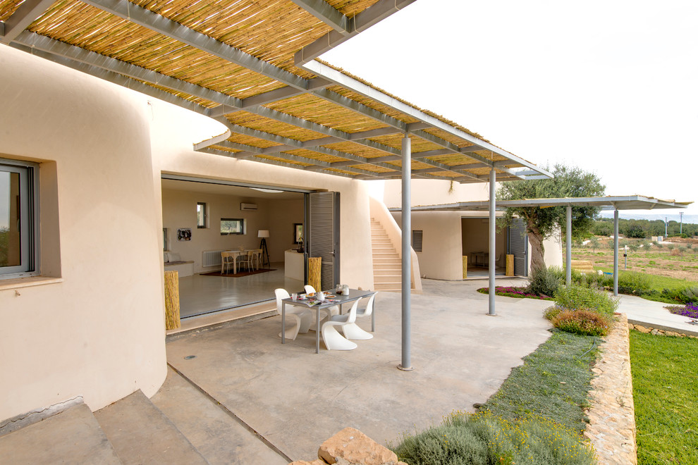 Photo of a large mediterranean patio in Rome with concrete pavers and a pergola.