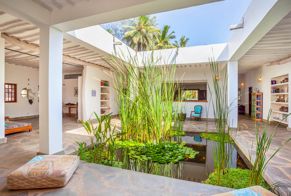 Idee per un patio o portico tropicale in cortile con nessuna copertura e pavimentazioni in pietra naturale