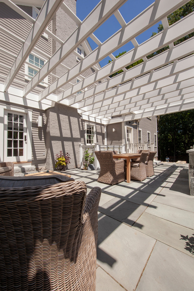 Réalisation d'une grande terrasse latérale minimaliste avec une cuisine d'été, des pavés en pierre naturelle et une pergola.