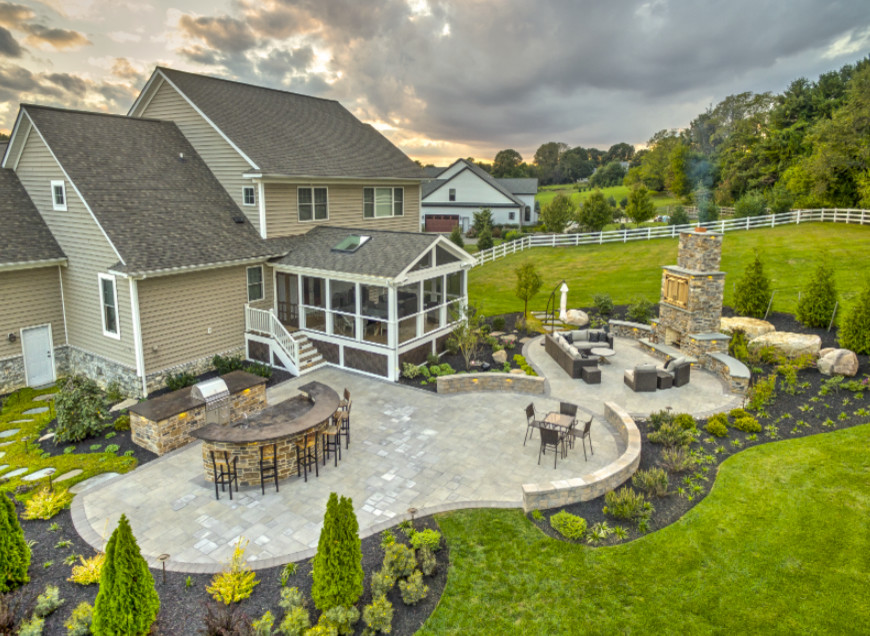 Cette photo montre une grande terrasse arrière craftsman avec une cuisine d'été, des pavés en pierre naturelle et aucune couverture.