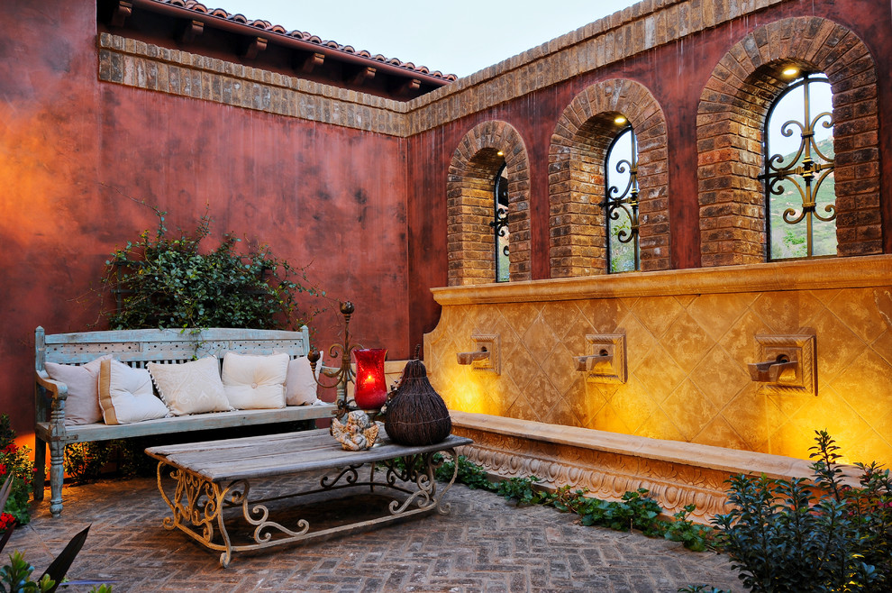 Foto de patio mediterráneo con adoquines de ladrillo y fuente
