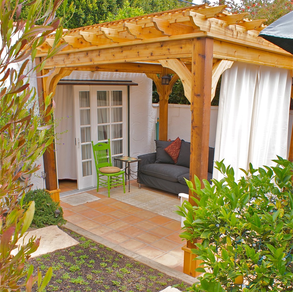 Immagine di un grande patio o portico mediterraneo dietro casa con piastrelle e una pergola