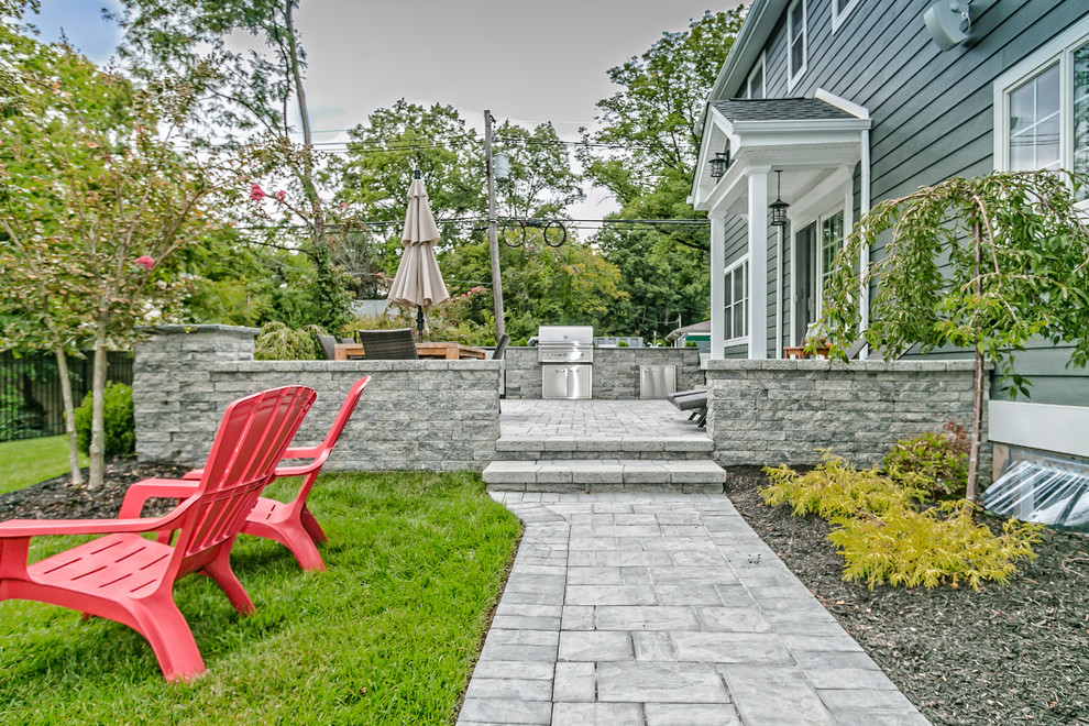 Modelo de patio minimalista grande en patio trasero con cocina exterior y adoquines de hormigón