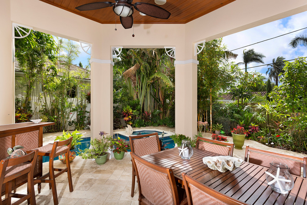 Diseño de patio tropical de tamaño medio en patio trasero y anexo de casas con adoquines de hormigón