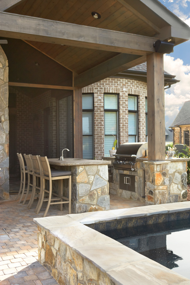Modelo de patio clásico pequeño en patio trasero con cocina exterior y adoquines de piedra natural