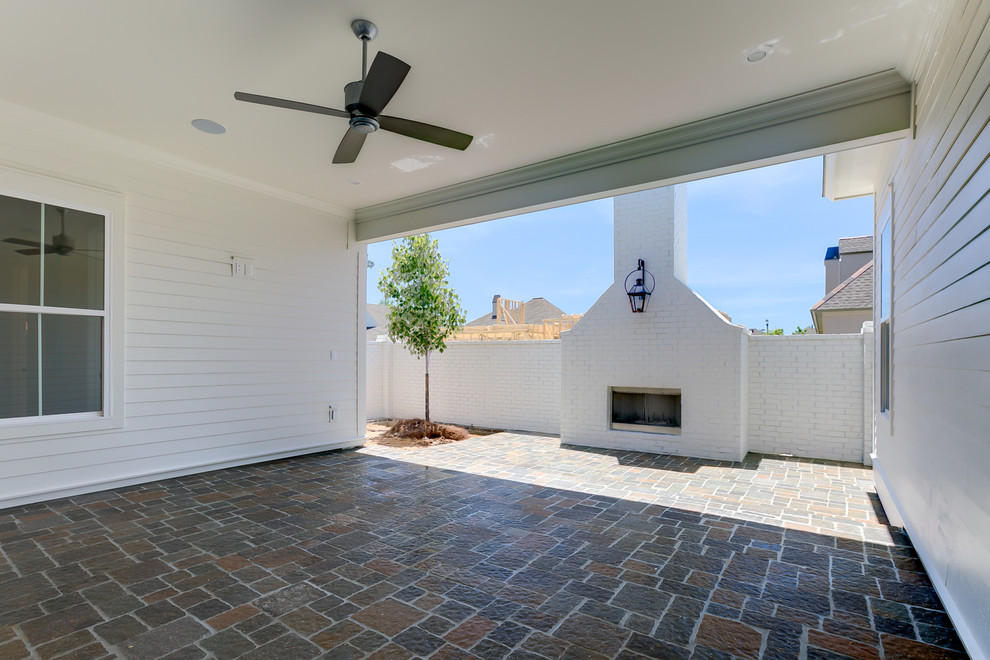 This is an example of a medium sized contemporary side patio in New Orleans with a fire feature, brick paving and a roof extension.