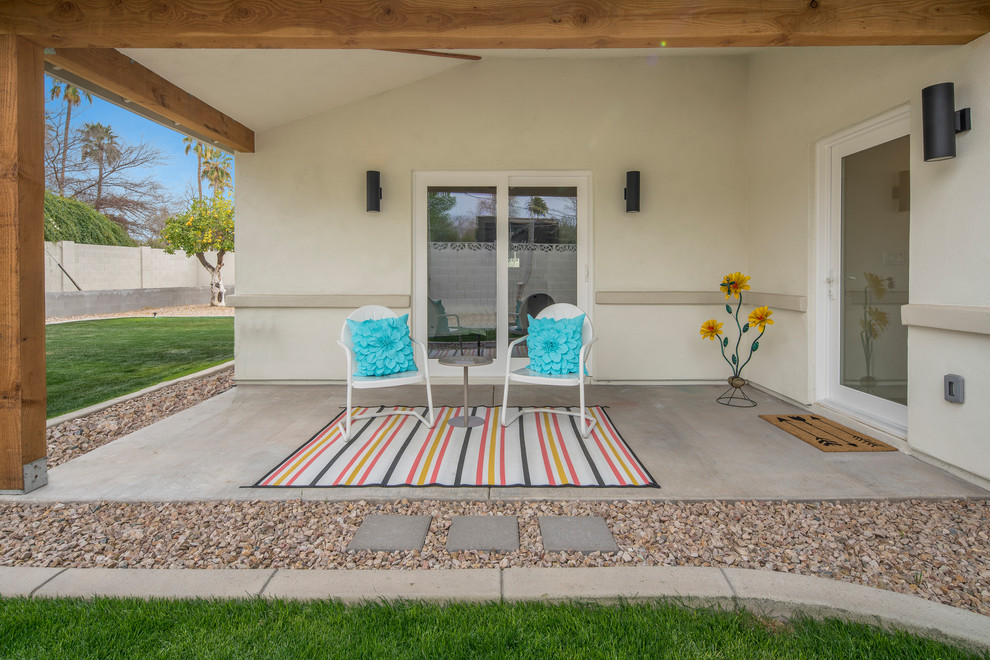 Retro back patio in Phoenix with concrete slabs and a roof extension.
