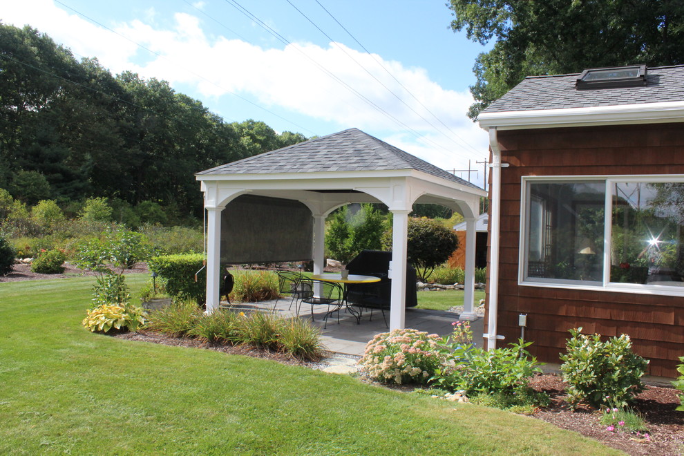 Aménagement d'une grande terrasse arrière classique avec une cuisine d'été, des pavés en pierre naturelle et un gazebo ou pavillon.