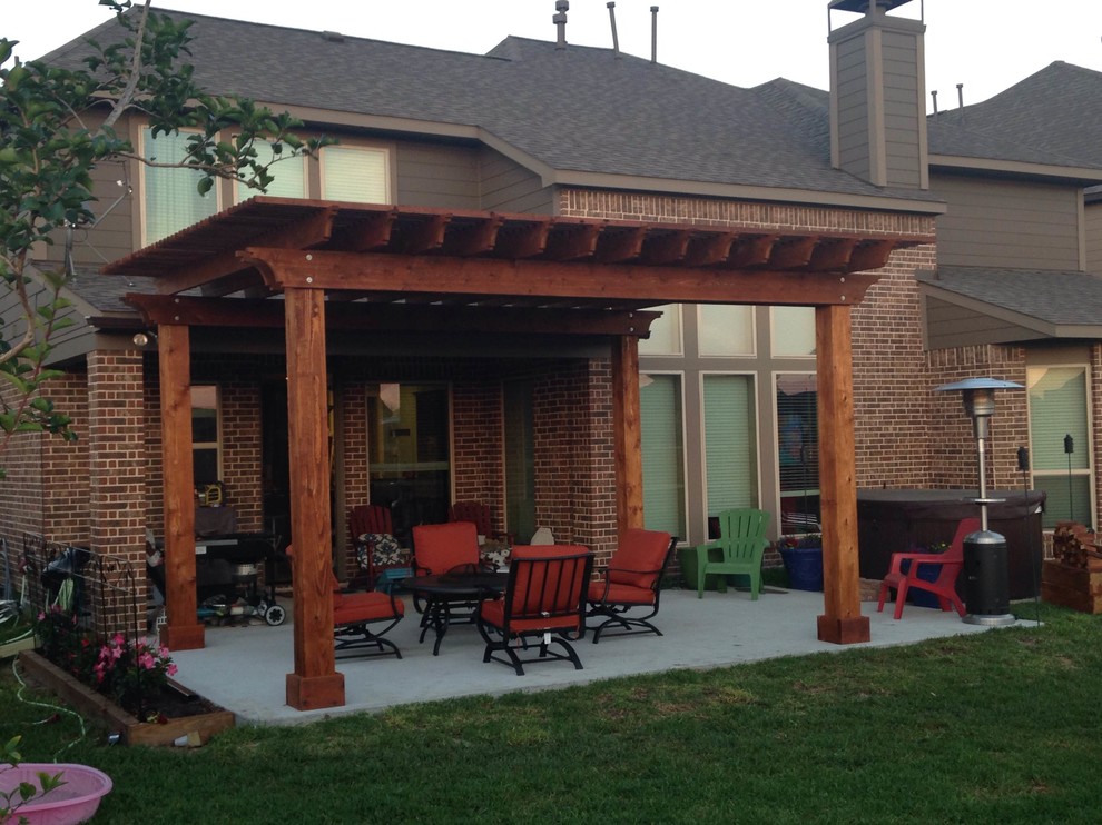 Esempio di un grande patio o portico tradizionale dietro casa con lastre di cemento e una pergola