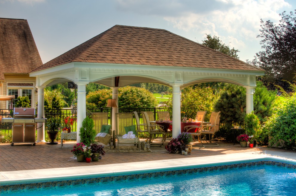 This is an example of a large classic back patio in Boston with an outdoor kitchen, natural stone paving and a gazebo.
