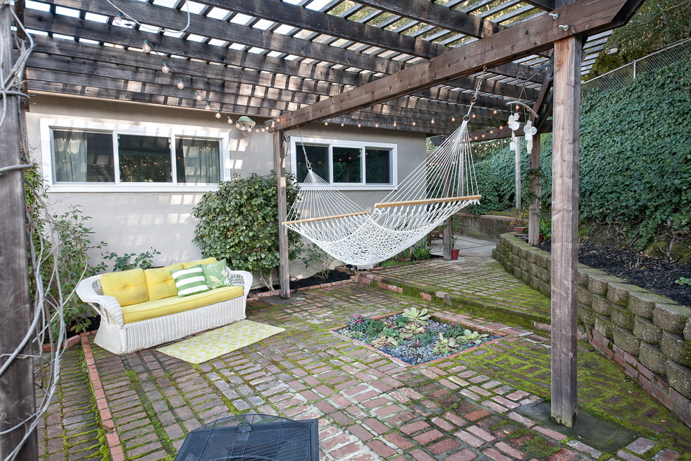 Diseño de patio retro de tamaño medio en patio trasero con adoquines de ladrillo y pérgola