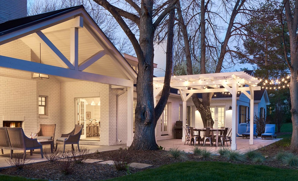 Esempio di un patio o portico chic dietro casa e di medie dimensioni con un focolare, lastre di cemento e un tetto a sbalzo