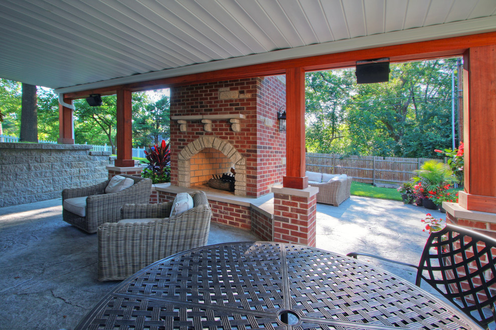Foto di un grande patio o portico chic dietro casa con un focolare, cemento stampato e un gazebo o capanno