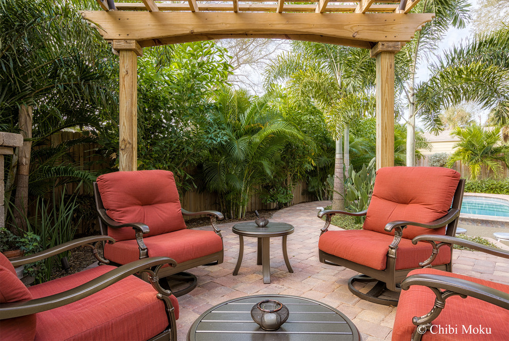 Inspiration for a small tropical backyard concrete paver patio remodel in Tampa with a pergola