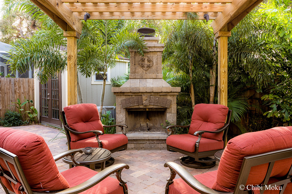 Photo of a small world-inspired back patio in Tampa with a fire feature, concrete paving and a pergola.