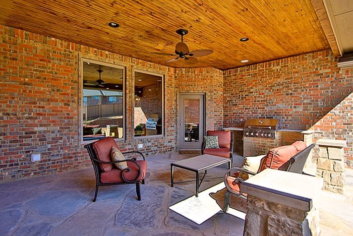 This is an example of a large rustic back patio in Oklahoma City with stamped concrete and a roof extension.